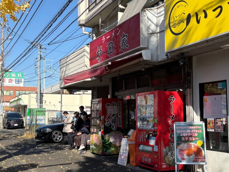 自販機が特徴的なラーメン杉田家本店の外観と行列の様子